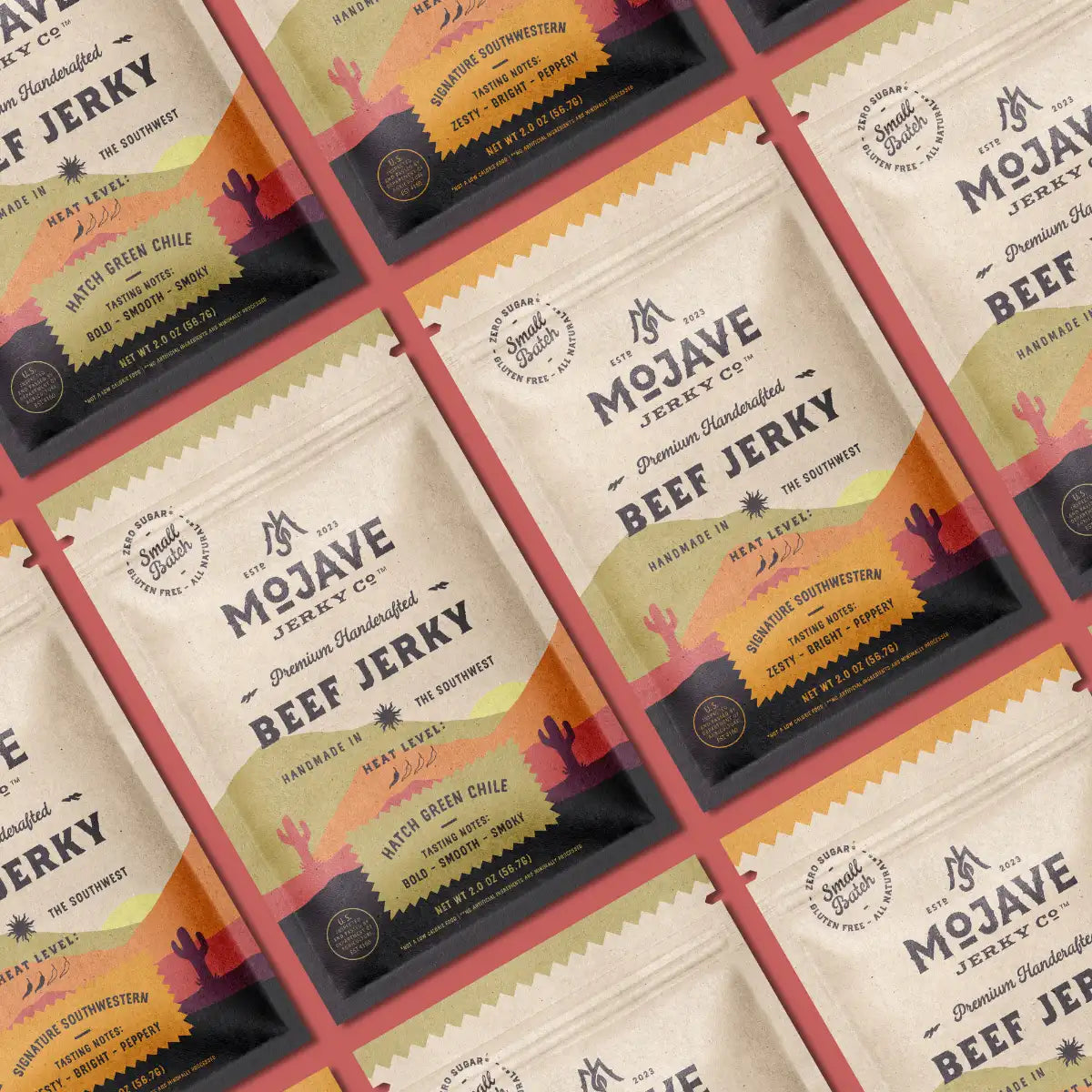 Mojave Jerky Co.'s two beef jerky flavors, Signature Southwestern and Hatch Green Chile, laid out on a red table.